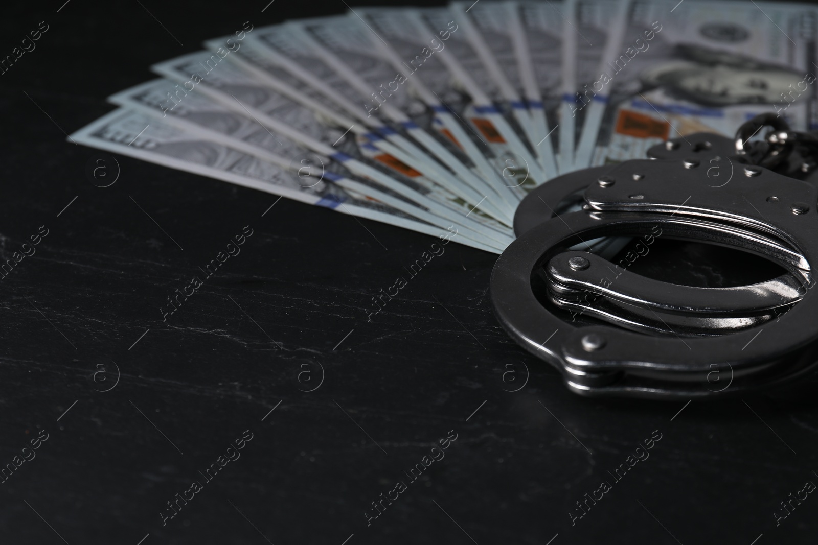 Photo of Corruption. Dollar banknotes and handcuffs on black table, closeup. Space for text