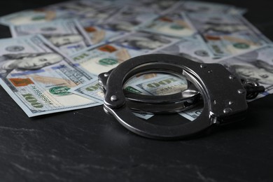 Corruption. Handcuffs and dollar banknotes on black table, closeup