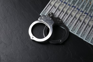 Corruption. Handcuffs and dollar banknotes on black table