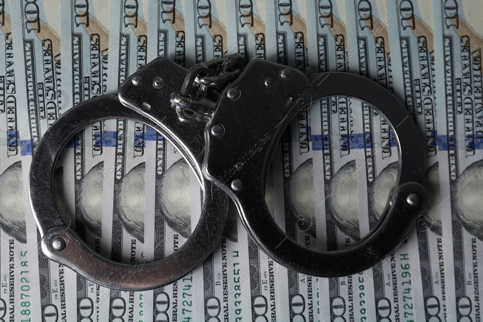 Photo of Corruption. Handcuffs on dollar banknotes, top view