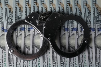 Corruption. Handcuffs on dollar banknotes, top view