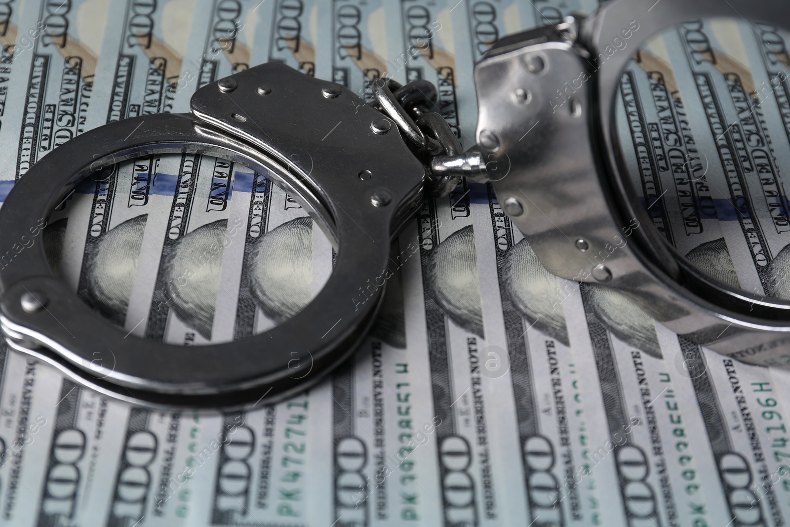 Photo of Corruption. Handcuffs on dollar banknotes, closeup view