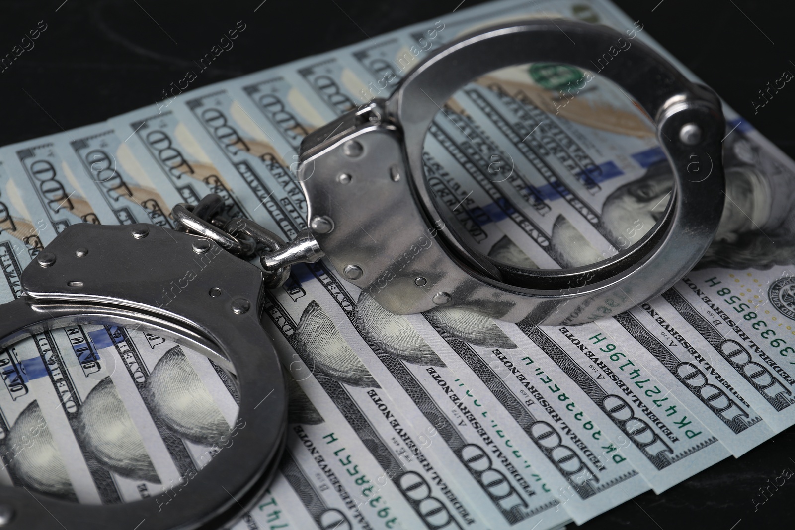 Photo of Corruption. Handcuffs and dollar banknotes on black table, closeup