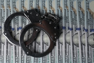 Corruption. Handcuffs on dollar banknotes, top view