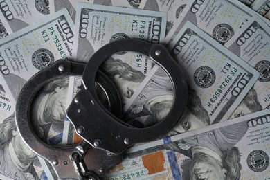 Corruption. Handcuffs on dollar banknotes, top view