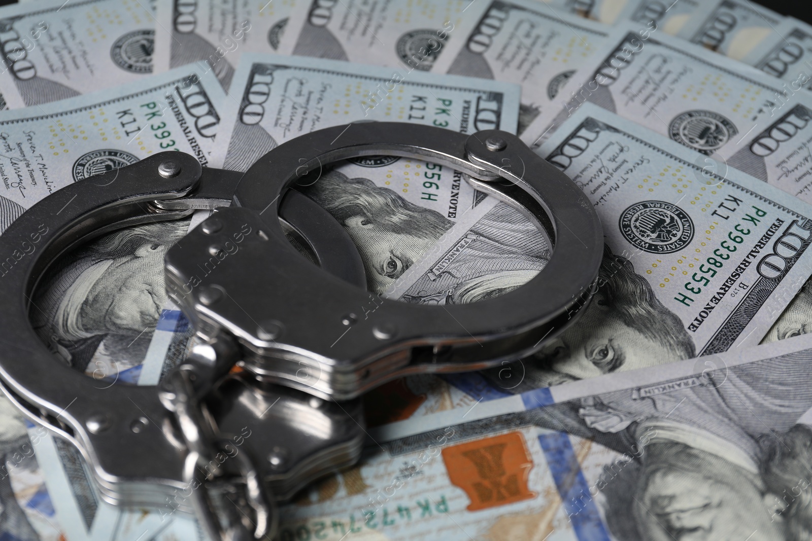 Photo of Corruption. Handcuffs on dollar banknotes, closeup view