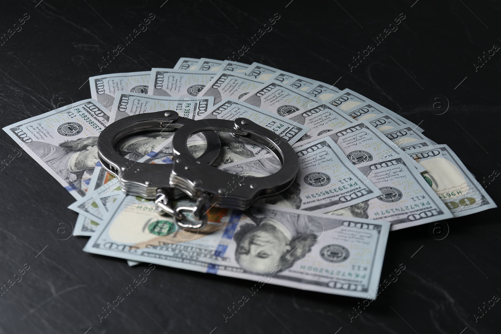 Photo of Corruption. Handcuffs and dollar banknotes on black table