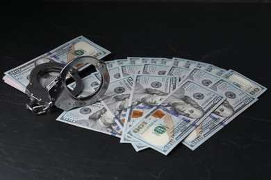 Corruption. Handcuffs and dollar banknotes on black table