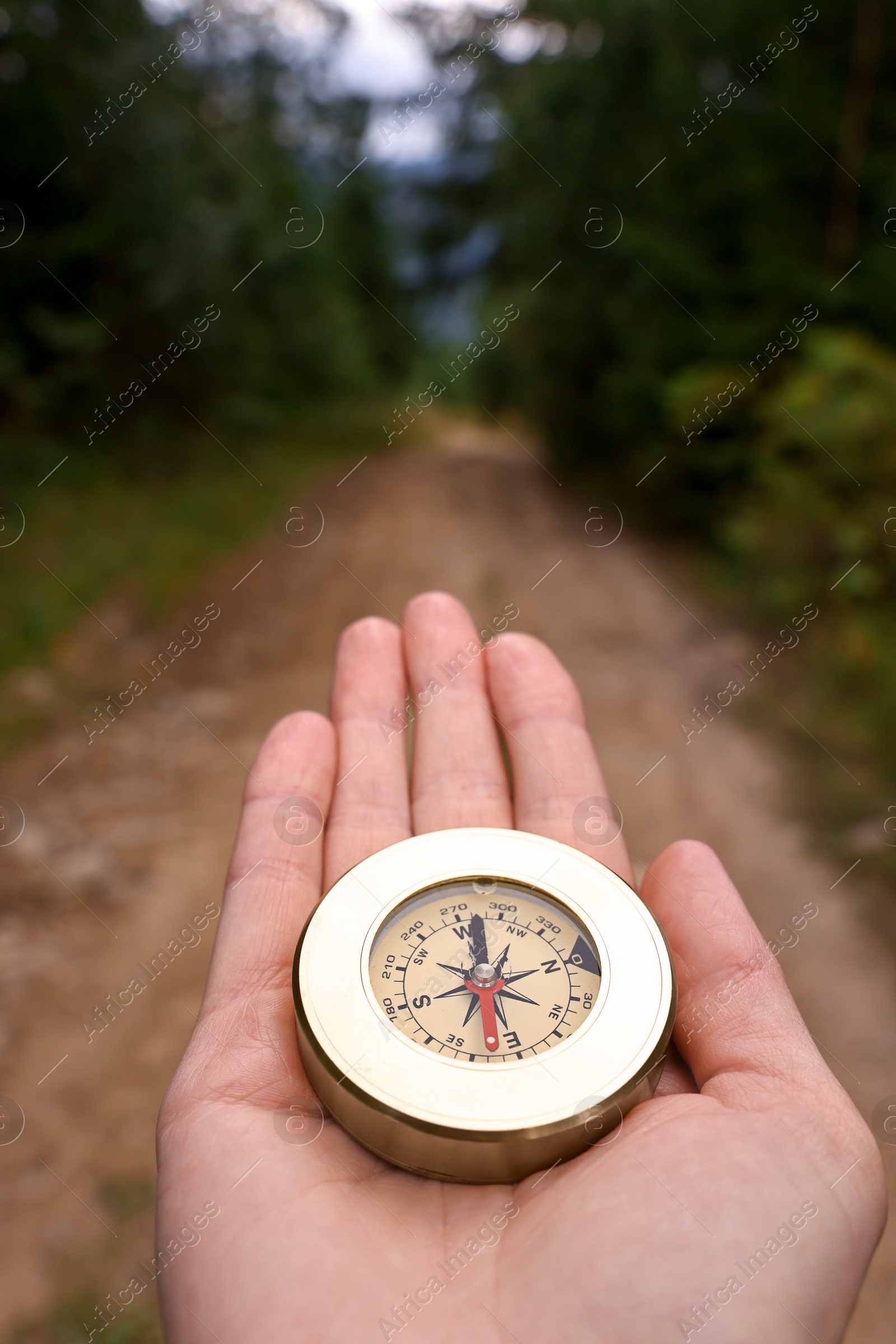 Photo of Woman holding compass near pathway outdoors, closeup