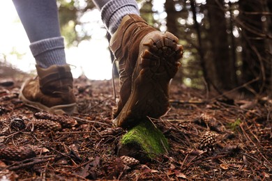 Photo of Hiker in trekking shoes walking in forest, closeup