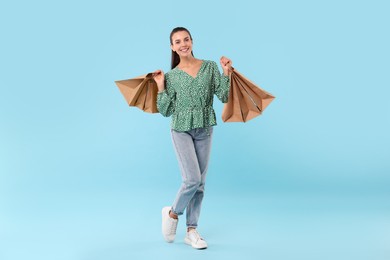 Photo of Smiling woman with shopping bags on light blue background