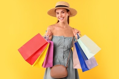 Photo of Smiling woman with colorful shopping bags on yellow background