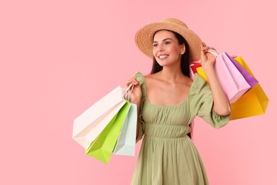 Photo of Smiling woman with colorful shopping bags on pink background. Space for text