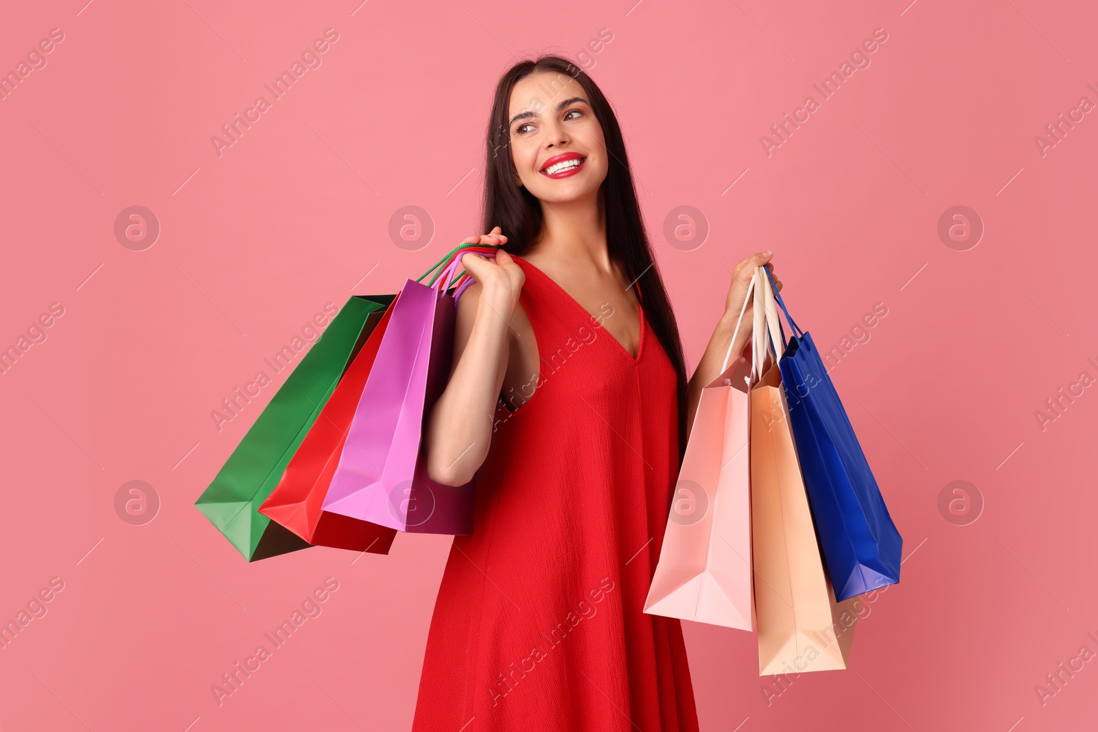 Photo of Smiling woman with colorful shopping bags on pink background