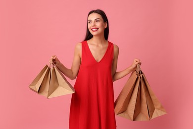 Smiling woman with shopping bags on pink background