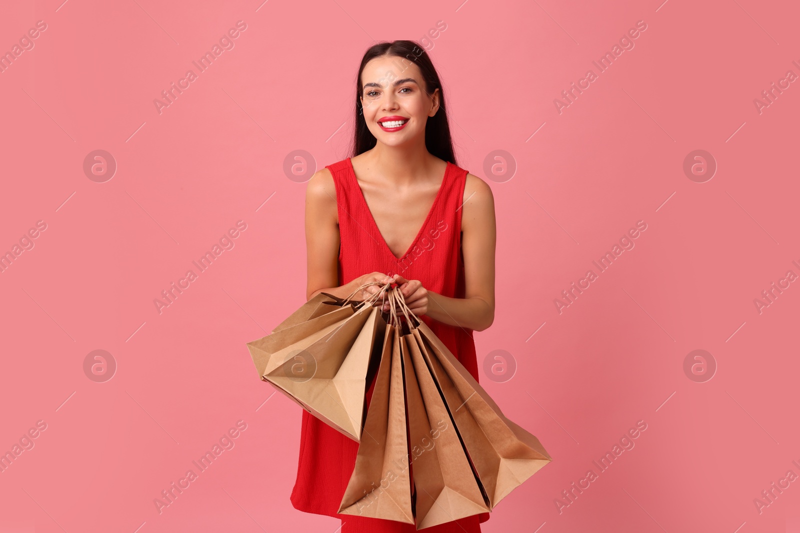 Photo of Smiling woman with shopping bags on pink background