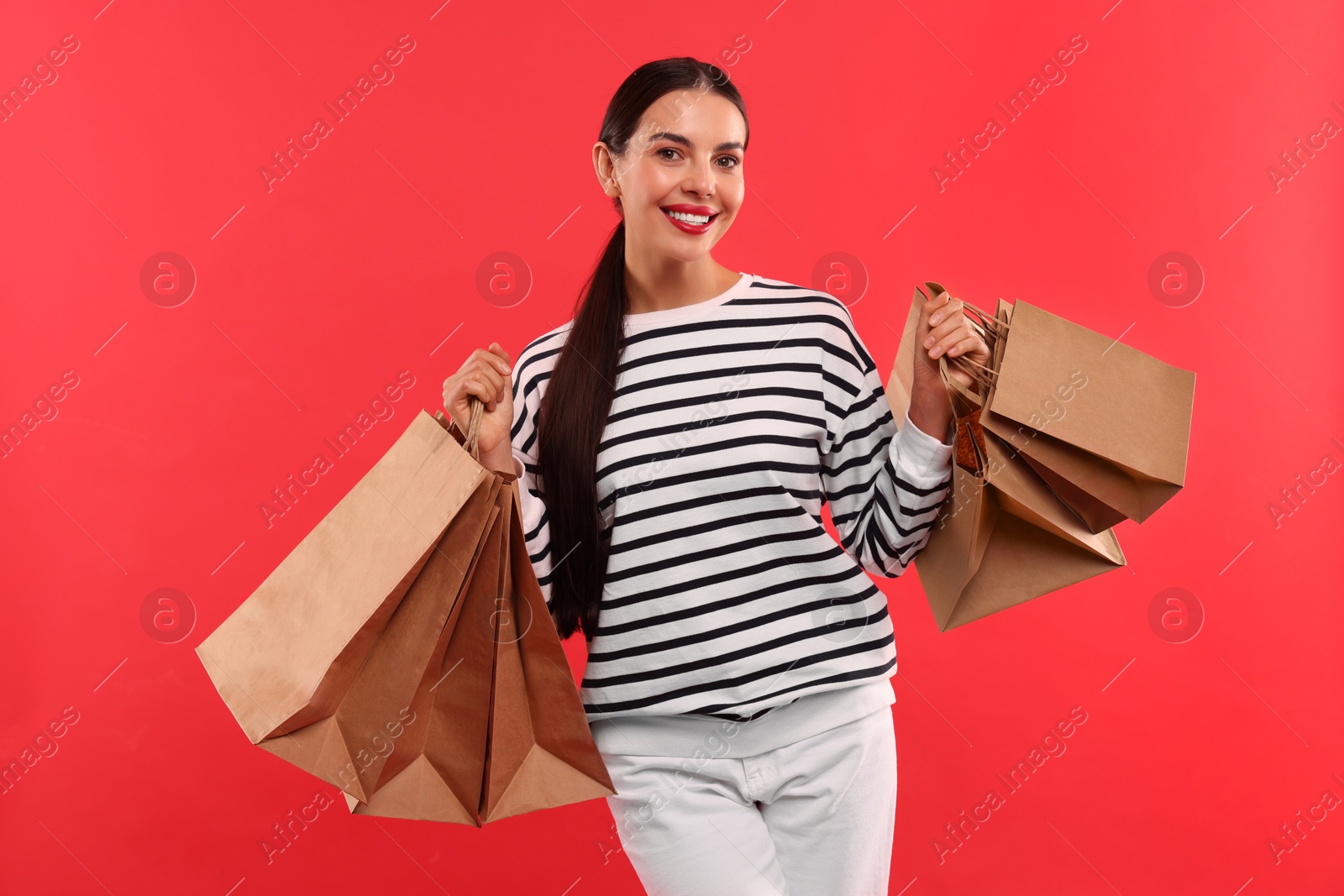 Photo of Smiling woman with shopping bags on red background