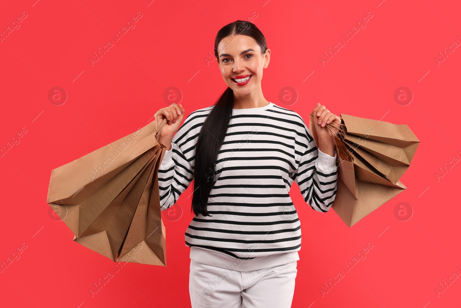 Photo of Smiling woman with shopping bags on red background