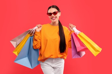 Smiling woman with colorful shopping bags on red background