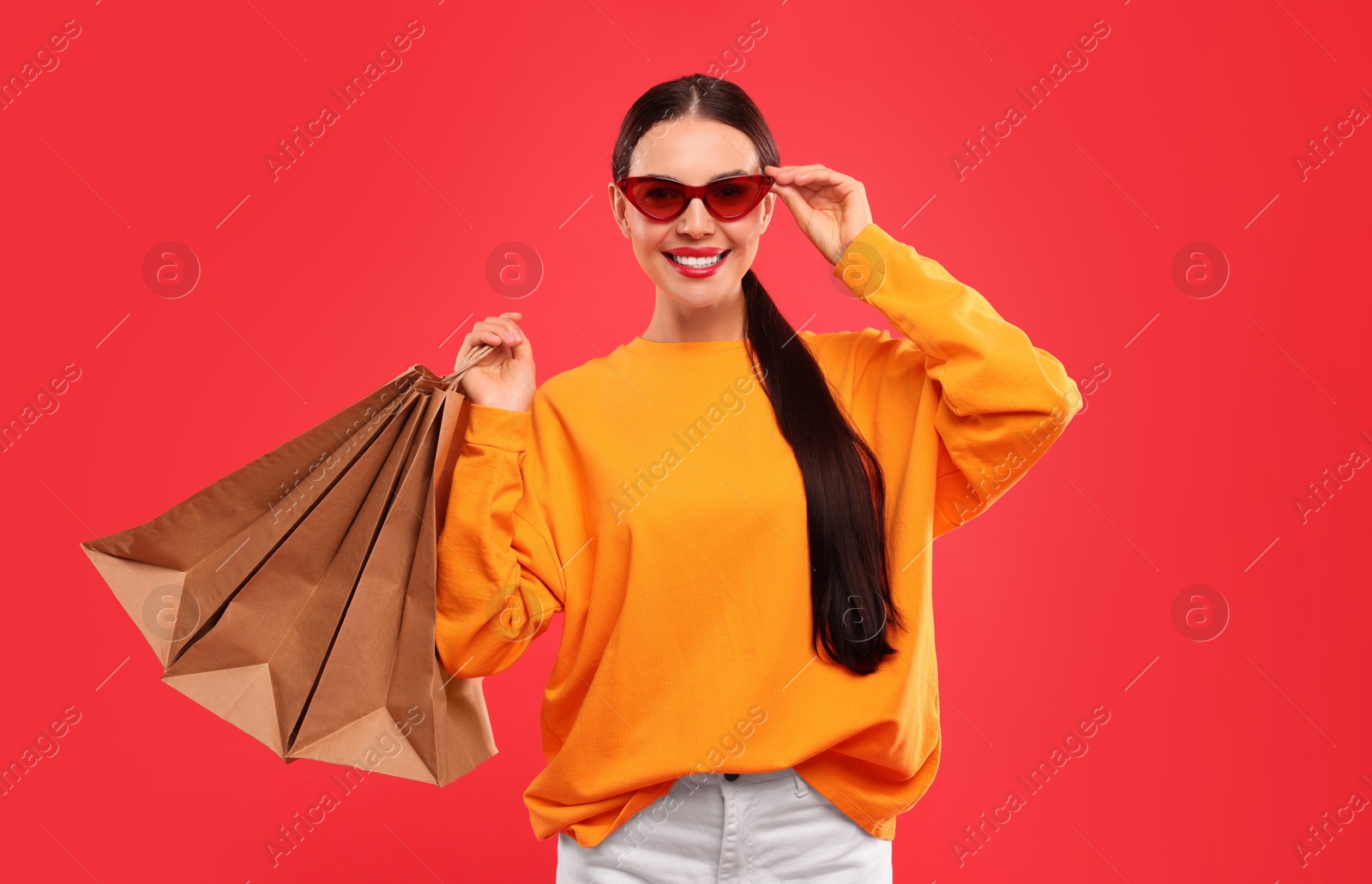 Photo of Smiling woman with shopping bags on red background