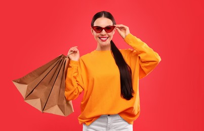 Smiling woman with shopping bags on red background