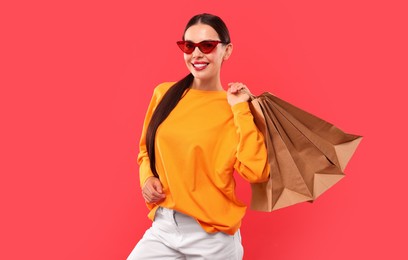 Smiling woman with shopping bags on red background