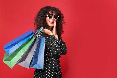 Photo of Happy woman with colorful shopping bags on red background. Space for text