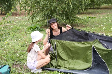 Mother and her daughter setting up camping tent outdoors