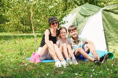 Photo of Mother and her kids spending time together near camping tent outdoors