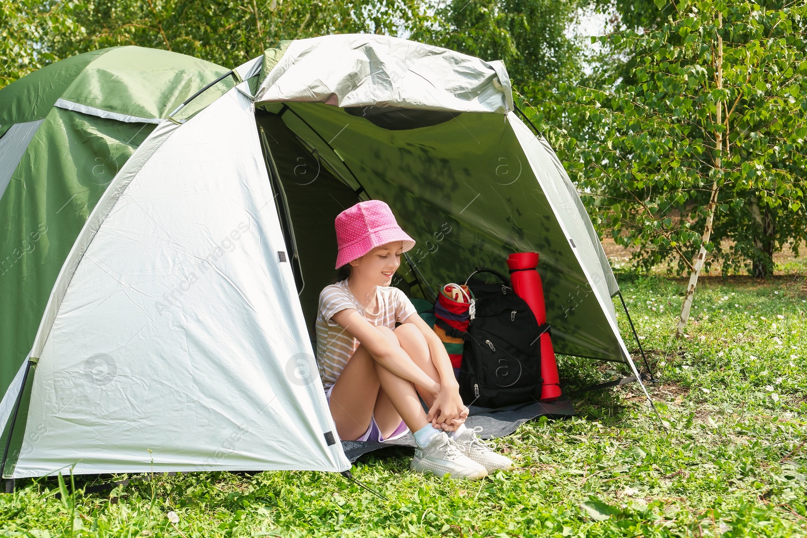 Photo of Cute girl sitting in camping tent outdoors