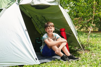 Photo of Cute boy sitting in camping tent outdoors