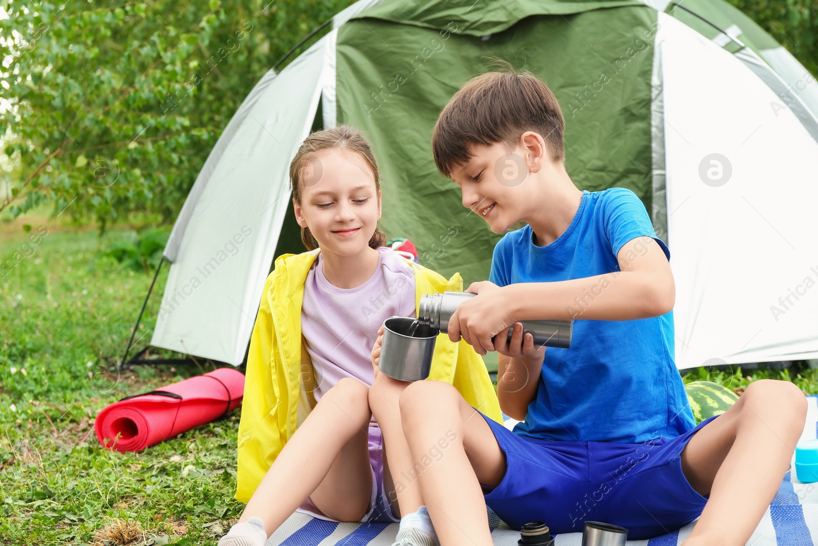 Photo of Cute kids enjoying hot drink near camping tent outdoors