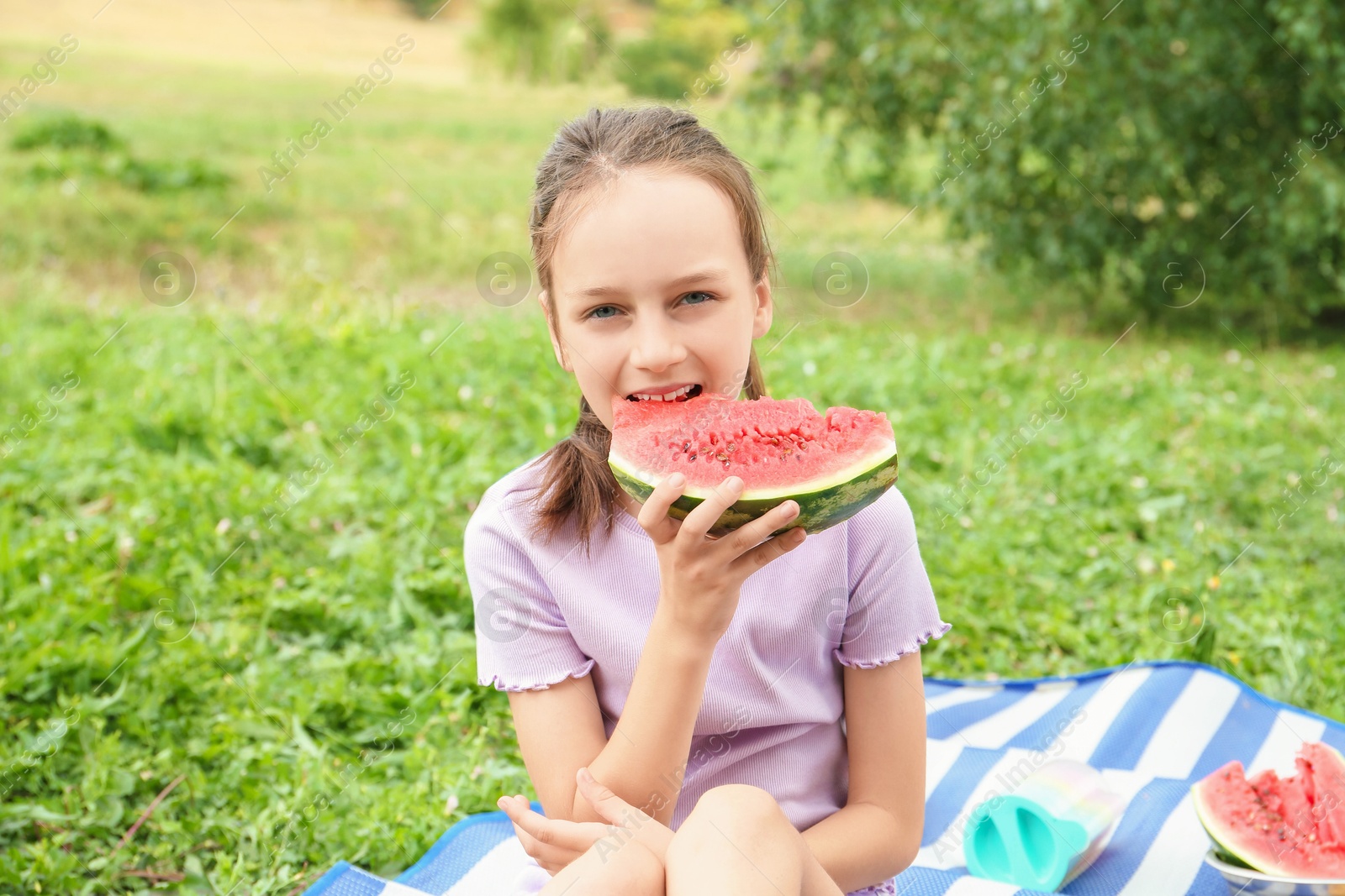 Photo of Girl eating slice of fresh watermelon outdoors