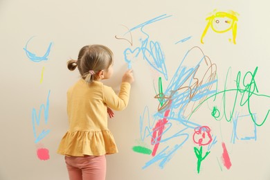 Image of Little child drawing on white wall, back view