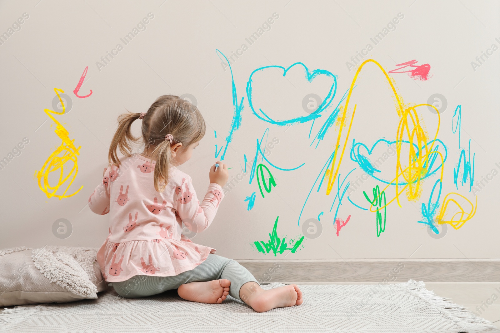 Image of Little child drawing on white wall, back view