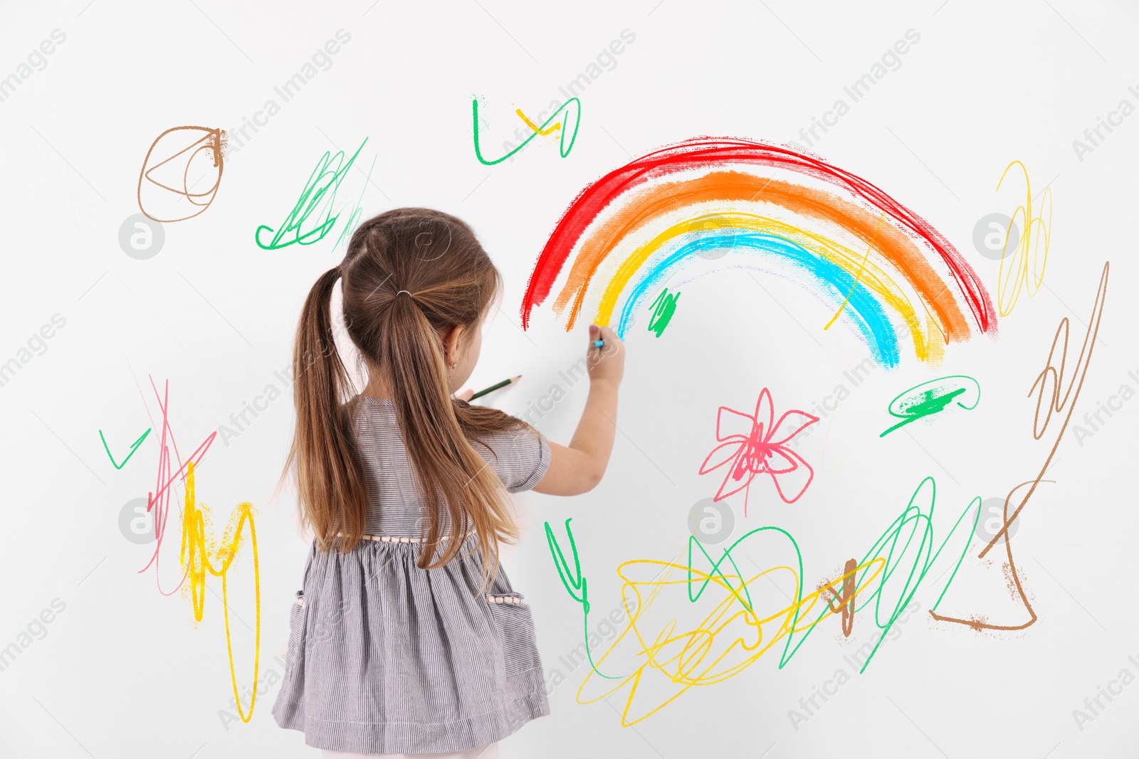 Image of Little child drawing on white wall, back view