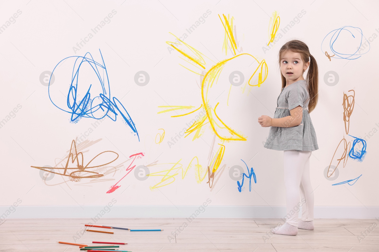 Image of Little child near white wall with drawings