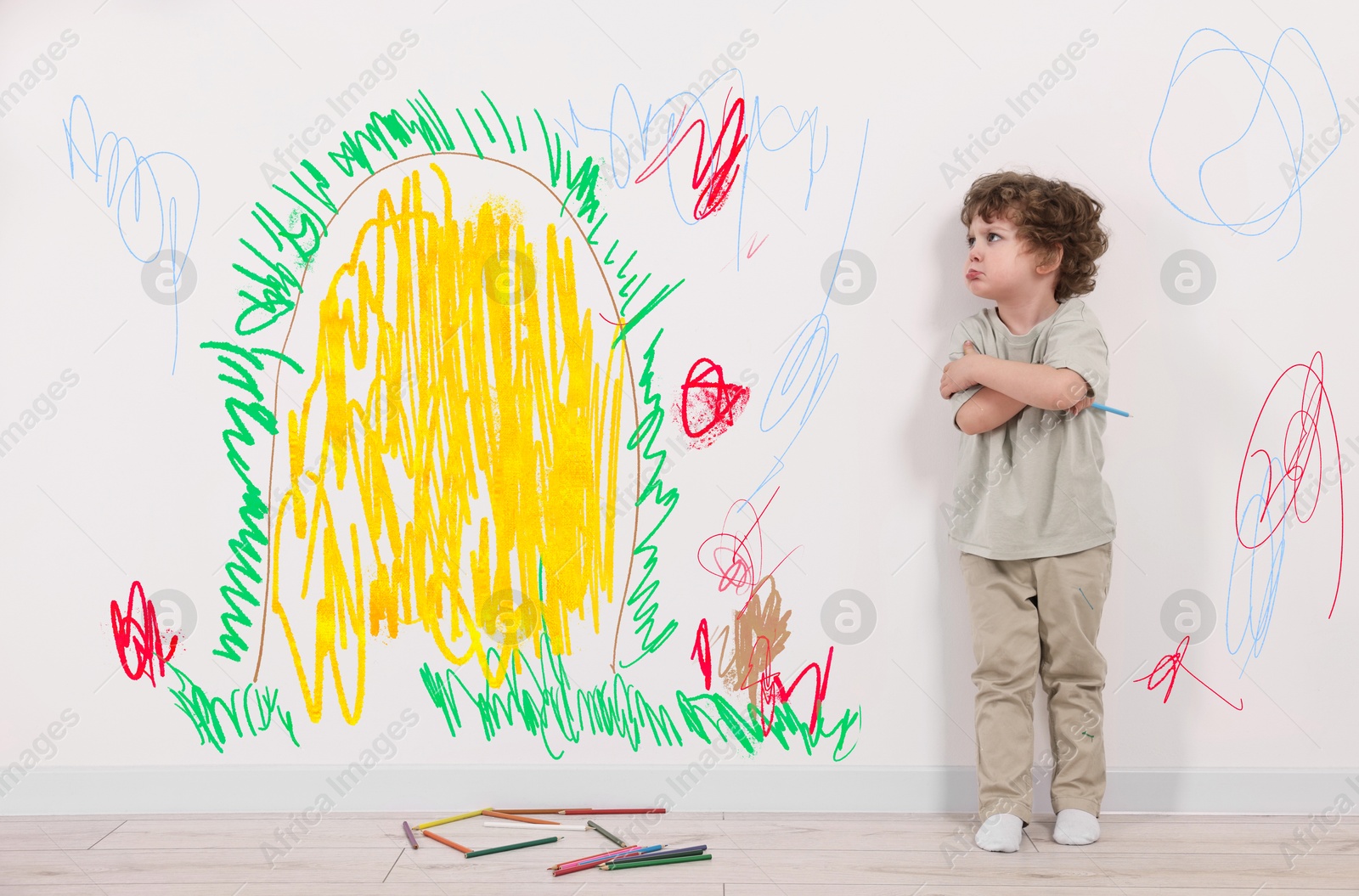 Image of Upset little child near white wall with drawings