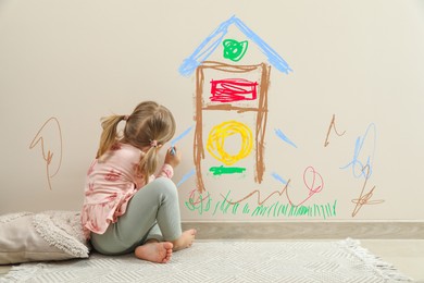 Little child drawing on white wall, back view