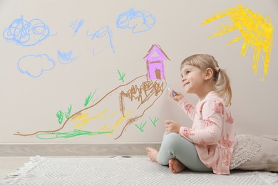 Image of Little child sitting on floor and drawing on white wall