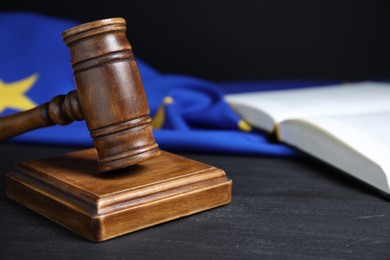 Judge's gavel, book and European Union flag on grey table against black background, closeup. Space for text