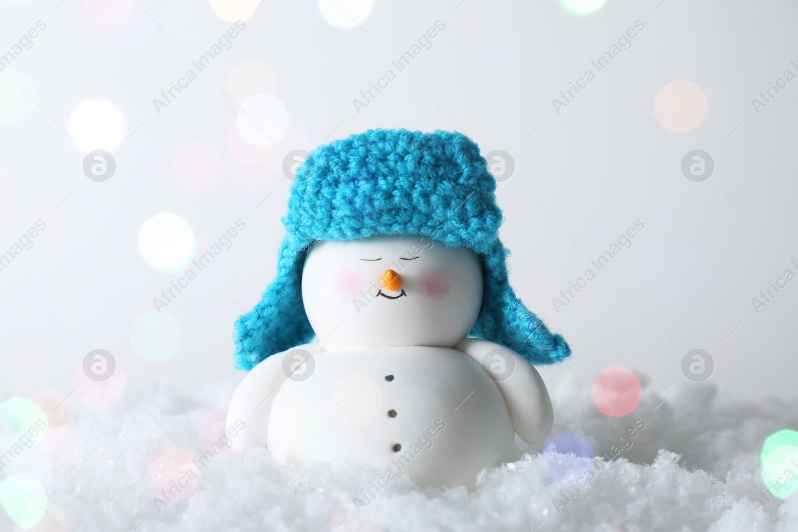 Photo of Cute decorative snowman on artificial snow against light background