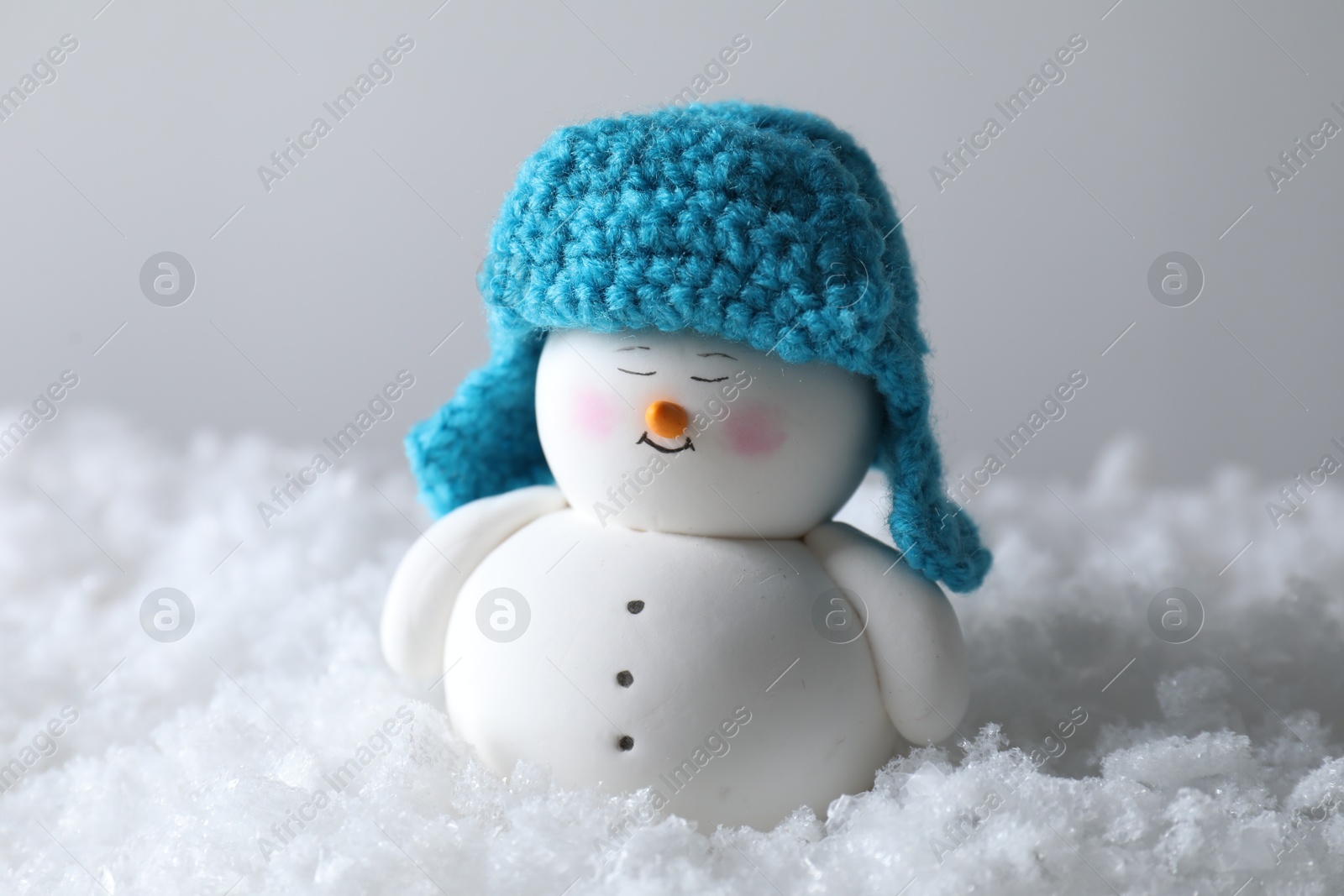 Photo of Cute decorative snowman on artificial snow against light background