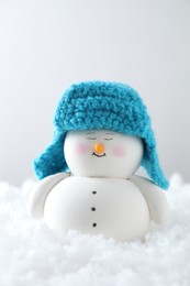 Photo of Cute decorative snowman on artificial snow against light background