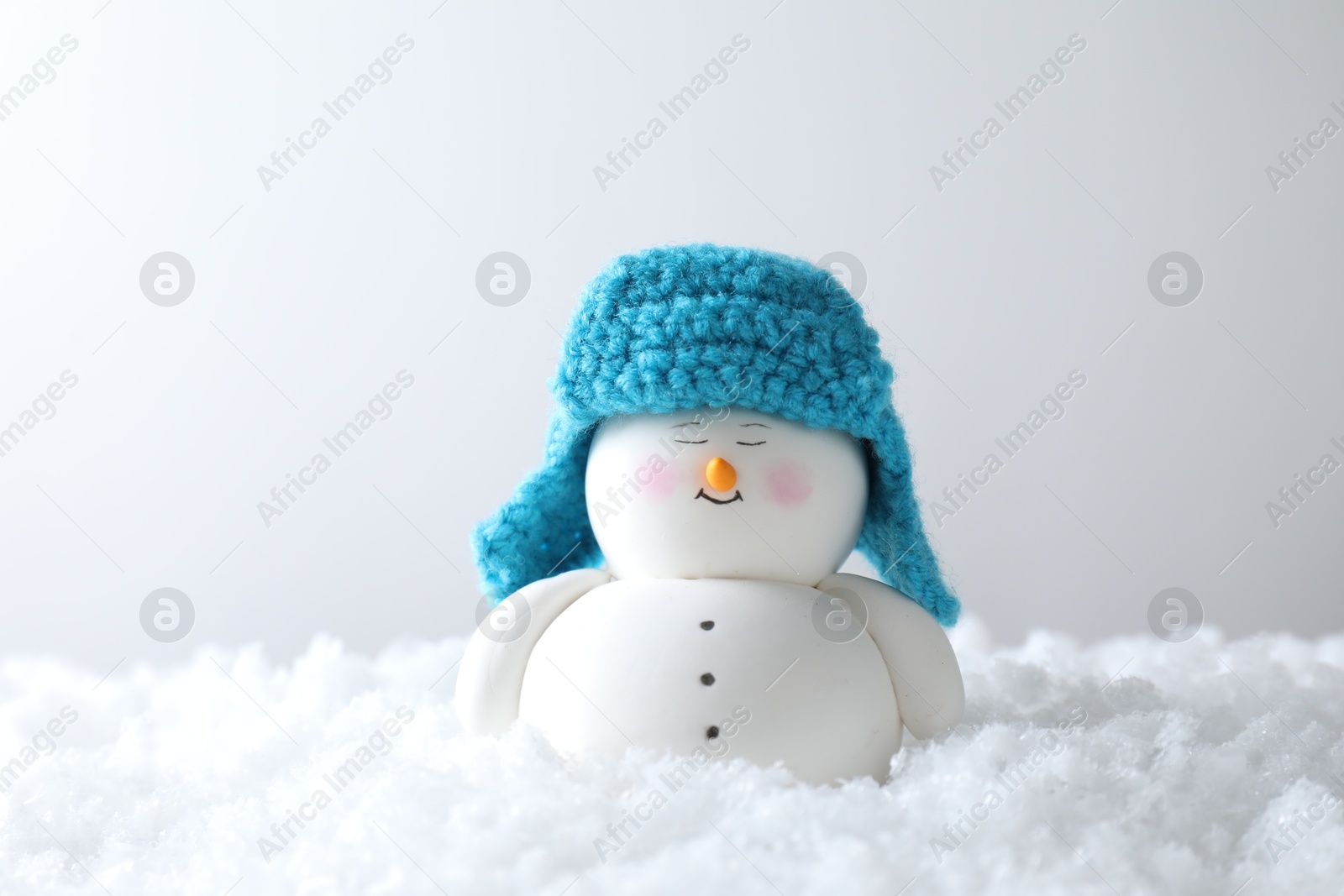 Photo of Cute decorative snowman on artificial snow against light background