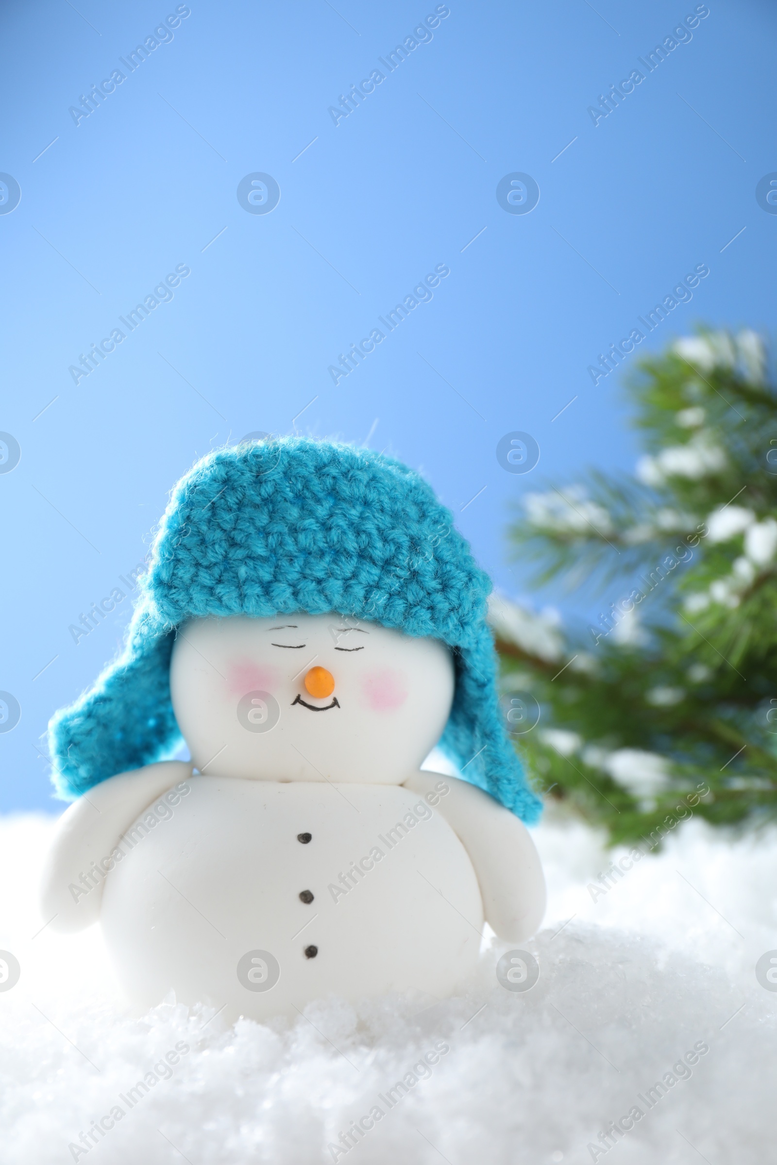 Photo of Cute decorative snowman on artificial snow against light blue background