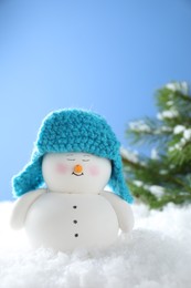 Photo of Cute decorative snowman on artificial snow against light blue background