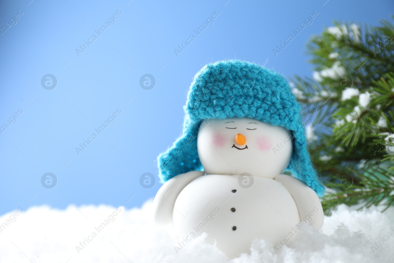 Photo of Cute decorative snowman on artificial snow against light blue background. Space for text