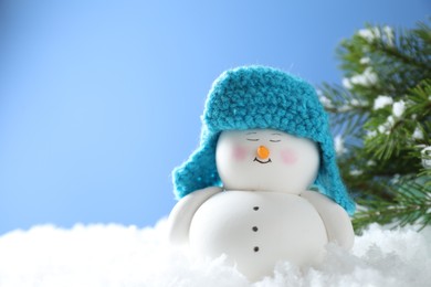 Photo of Cute decorative snowman on artificial snow against light blue background. Space for text