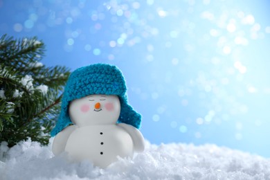 Photo of Cute decorative snowman and fir branches on artificial snow against blurred lights. Space for text